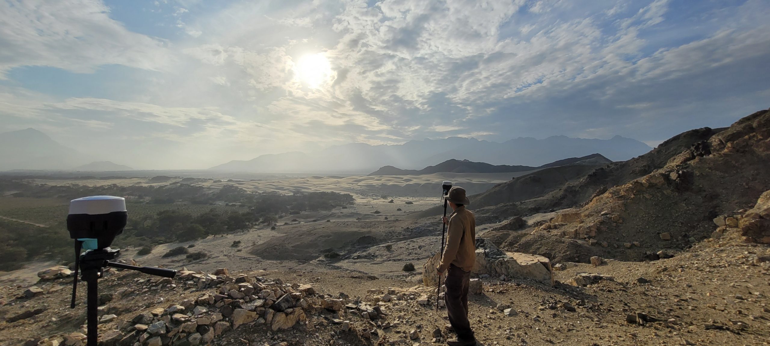 Man standing in front of vast bare mountains.